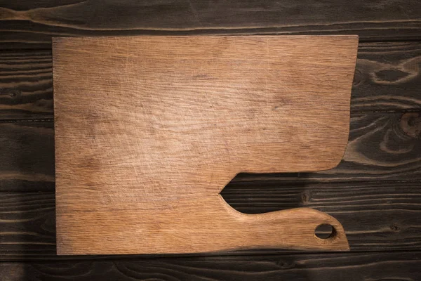 Vista superior de tabla de cortar de madera en la mesa marrón - foto de stock