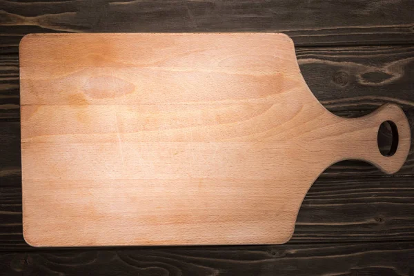 Top view of wooden cutting board on brown table — Stock Photo