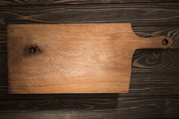 Top view of wooden cutting board on brown table — Stock Photo