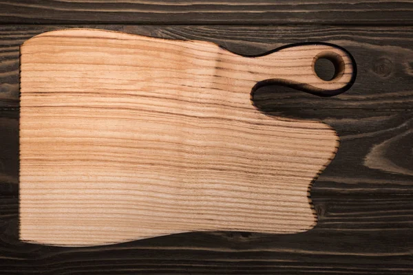 Top view of wooden cutting board on brown table — Stock Photo