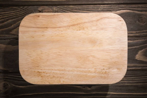 Top view of wooden cutting board on brown table — Stock Photo