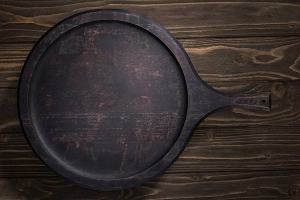 Top view of black cutting board on brown table — Stock Photo