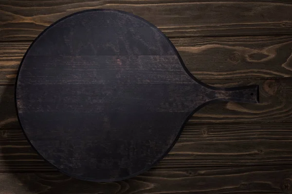 Top view of black cutting board on brown table — Stock Photo