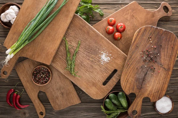 Top view of cutting boards, cherry tomatoes, salt, garlics, cucumbers, chili peppers and spices — Stock Photo