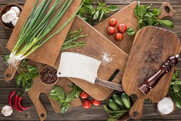 Top view of cutting boards, cherry tomatoes, salt, garlics, cucumbers, chili peppers, pepper mill, meat chopper and spices — Stock Photo