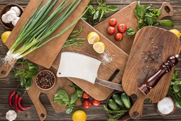 Top view of cutting boards, cherry tomatoes, salt, garlics, cucumbers, chili peppers, pepper mill, meat chopper, lemons and spices — Stock Photo