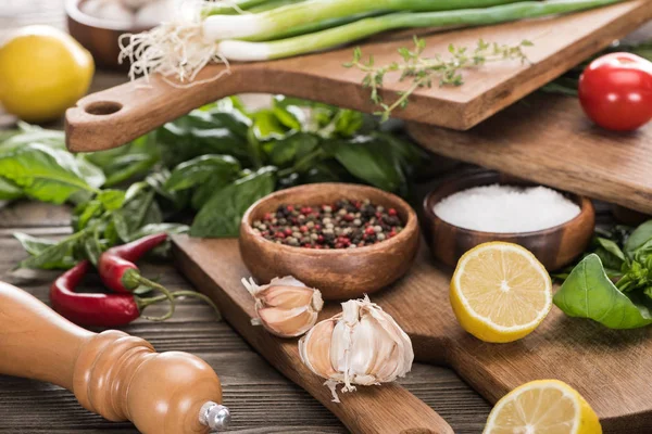 Selective focus of green onion, cutting boards, lemons, chili peppers, salt mill, salt, spices, greenery and garlics — Stock Photo