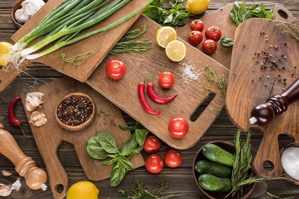 Top view of cutting boards, cherry tomatoes, salt, garlics, cucumbers, chili peppers, pepper mill, salt mill, lemons and spices — Stock Photo