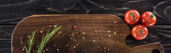 Panoramic shot of wooden chopping board with spices, rosemary and cherry tomatoes — Stock Photo