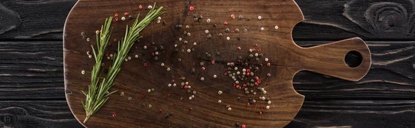 Panoramic shot of wooden chopping board with spices and rosemary — Stock Photo