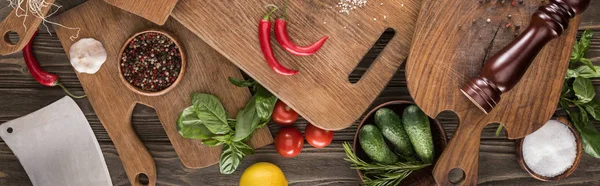 Panoramische Aufnahme von Schneidebrettern, Kirschtomaten, Salz, Knoblauch, Gurken, Chilischoten, Pfeffermühle, Fleischhacker, Zitrone und Gewürzen — Stockfoto