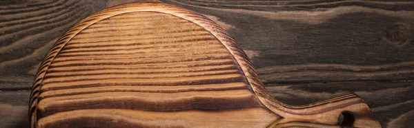 Panoramic shot of wooden cutting board on brown table — Stock Photo