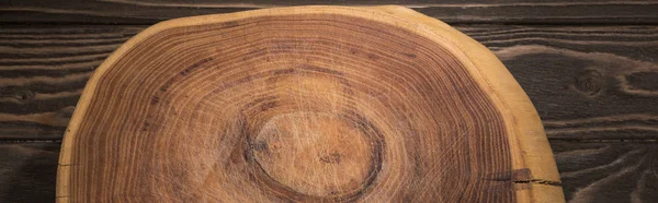 Panoramic shot of wooden cutting board on brown table — Stock Photo