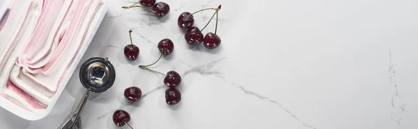 Vista dall'alto del delizioso gelato vicino al cucchiaio di gelato e ciliegie su sfondo grigio marmo, colpo panoramico — Foto stock