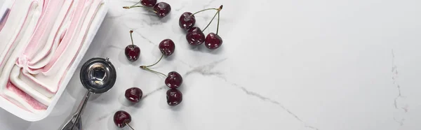 Vista superior de delicioso helado cerca de cuchara de helado y cerezas sobre fondo gris mármol, plano panorámico - foto de stock