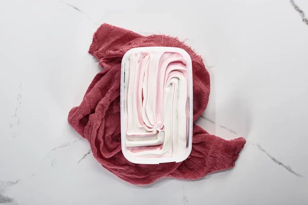Вид зверху смачне морозиво на рожевій тканині на мармуровому сірому фоні — стокове фото
