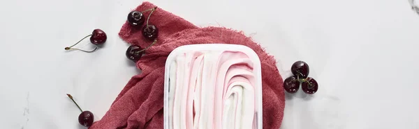 Vue du dessus de délicieuse crème glacée près de tissu rose et cerises sur fond gris marbre, panoramique — Photo de stock