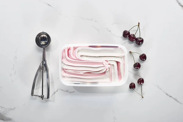 Vista superior de la cuchara de helado, cerezas y helado sobre fondo gris mármol - foto de stock