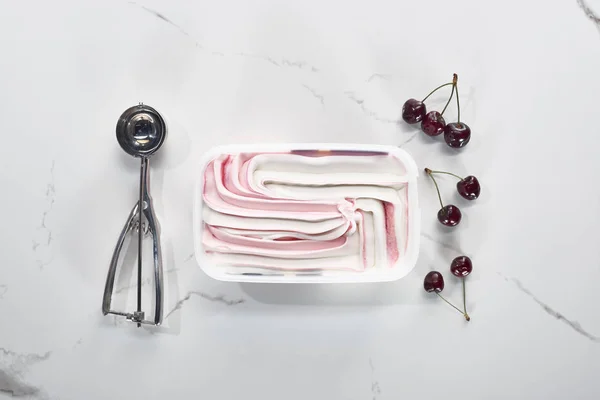 Top view of ice cream spoon, cherries and ice cream on marble grey background — Stock Photo