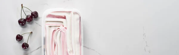 Vista superior de deliciosas cerezas frescas y helado sobre fondo gris mármol, plano panorámico - foto de stock