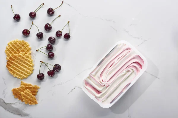 Blick von oben auf leckere Waffeln, Kirschen und Eis auf marmorgrauem Hintergrund — Stockfoto