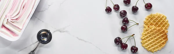 Vista superior de deliciosos gofres, cuchara y cerezas y helado sobre fondo gris mármol, plano panorámico - foto de stock