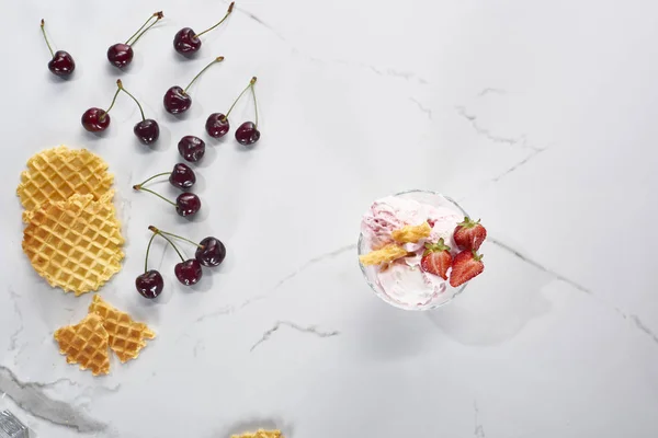 Vue de dessus de délicieuse crème glacée aux gaufres et fraises près des cerises sur fond gris marbre — Photo de stock