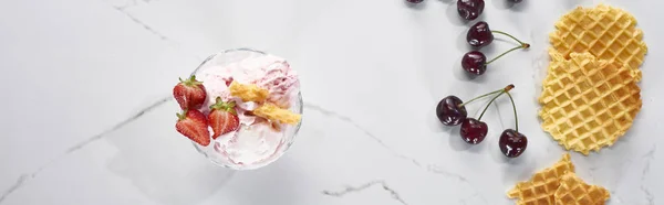 Top view of delicious ice cream with waffles and strawberries near cherries on marble grey background, panoramic shot — Stock Photo