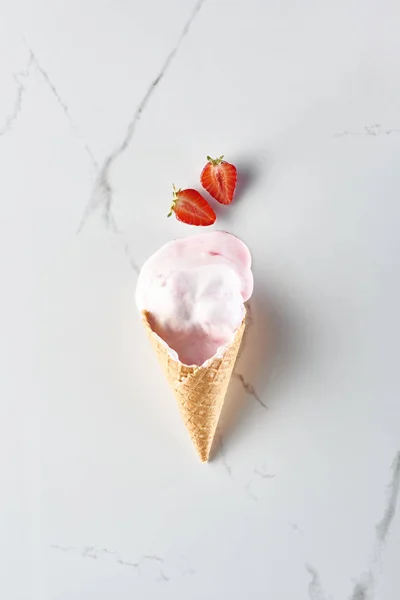 Top view of delicious ice cream in waffle cone near strawberries on marble grey background — Stock Photo