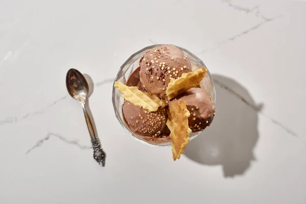 Vue du dessus de la cuillère et délicieuse crème glacée au chocolat dans un bol avec gaufres sur fond gris marbre — Photo de stock