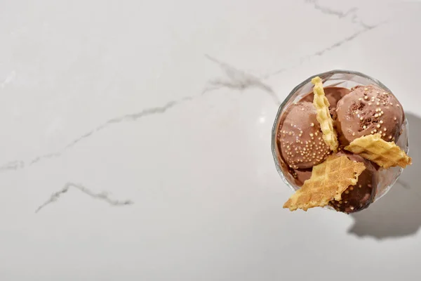 Vue du dessus de délicieuse crème glacée au chocolat dans un bol avec gaufres sur fond gris marbre — Photo de stock