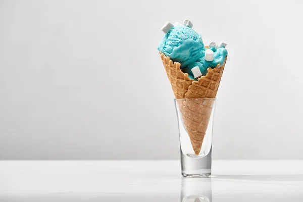 Leckeres süßes blaues Eis mit Marshmallows in knusprigen Waffelkegel isoliert auf grau — Stockfoto