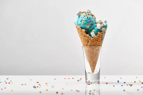 Delicioso sorvete azul doce com marshmallows e polvilhas em cone de waffle crocante isolado em cinza — Fotografia de Stock