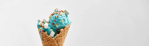 Delicioso helado azul dulce con malvaviscos y salpicaduras en cono de gofre crujiente aislado en gris, tiro panorámico - foto de stock