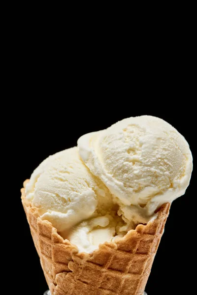 Vista de cerca del delicioso helado de vainilla en cono de gofre crujiente aislado en negro - foto de stock