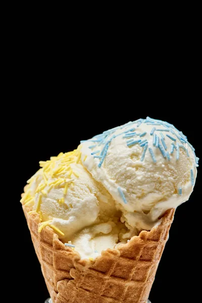 Close up view of delicious vanilla ice cream with sprinkles in crispy waffle cone isolated on black — Stock Photo