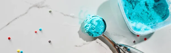 Top view of delicious blue ice cream with sprinkles in box with ice cream spoon on marble grey background, panoramic shot — Stock Photo