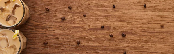 Vue du dessus du café glacé dans les verres près des grains de café sur la table en bois, vue panoramique — Photo de stock