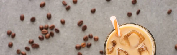 Foco seletivo de café gelado em vidro com palha e grãos de café em fundo cinza, tiro panorâmico — Fotografia de Stock