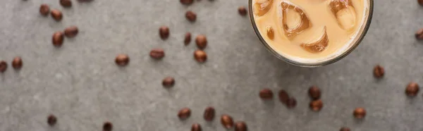 Selective focus of ice coffee in glass and coffee grains on grey background, panoramic shot — Stock Photo