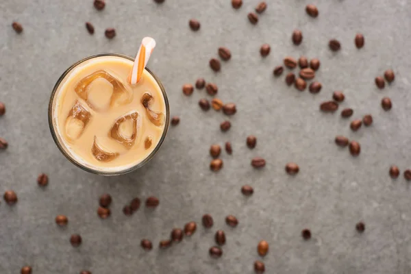 Selektiver Fokus von Eiskaffee im Glas mit Stroh- und Kaffeekörnern auf grauem Hintergrund — Stockfoto