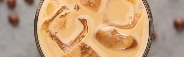 Близкий вид на ледяной кофе в стакане с соломой и зерном кофе на сером фоне, панорамный снимок — стоковое фото