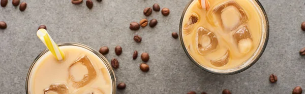 Top view of ice coffee with straws and coffee grains on grey background, panoramic shot — Stock Photo