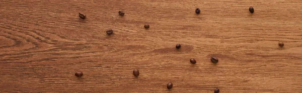 Vista dall'alto di chicchi di caffè sparsi su tavolo di legno, colpo panoramico — Foto stock