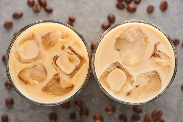 Vista superior de café gelado fresco em copos e grãos de café em fundo cinza — Fotografia de Stock