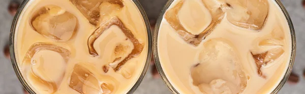 Close up view of fresh ice coffee in glasses and coffee grains on grey background, panoramic shot — Stock Photo