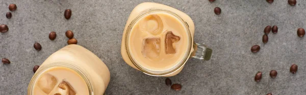 Vue de dessus du café glacé dans des bocaux en verre et grains de café sur fond gris, panoramique — Photo de stock