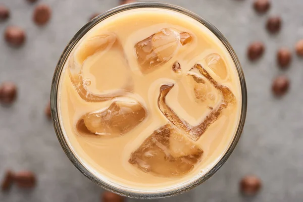 Vue rapprochée du café glacé en verre avec paille et grains de café sur fond gris — Photo de stock