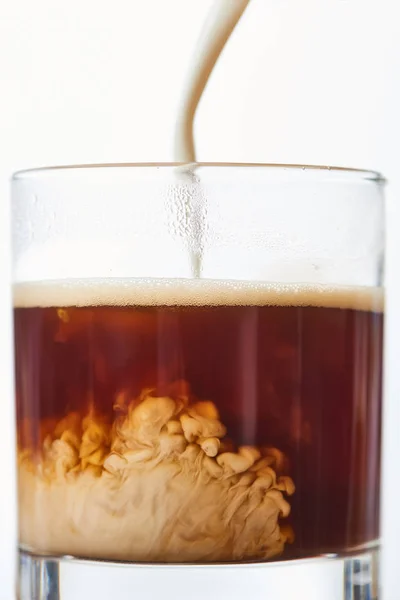 Close up view of mil poring to coffee in glass isolated on white — Stock Photo