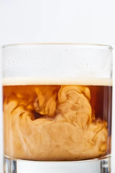 Близкий вид кофе смешивания с молоком в стакане изолированы на белом — стоковое фото